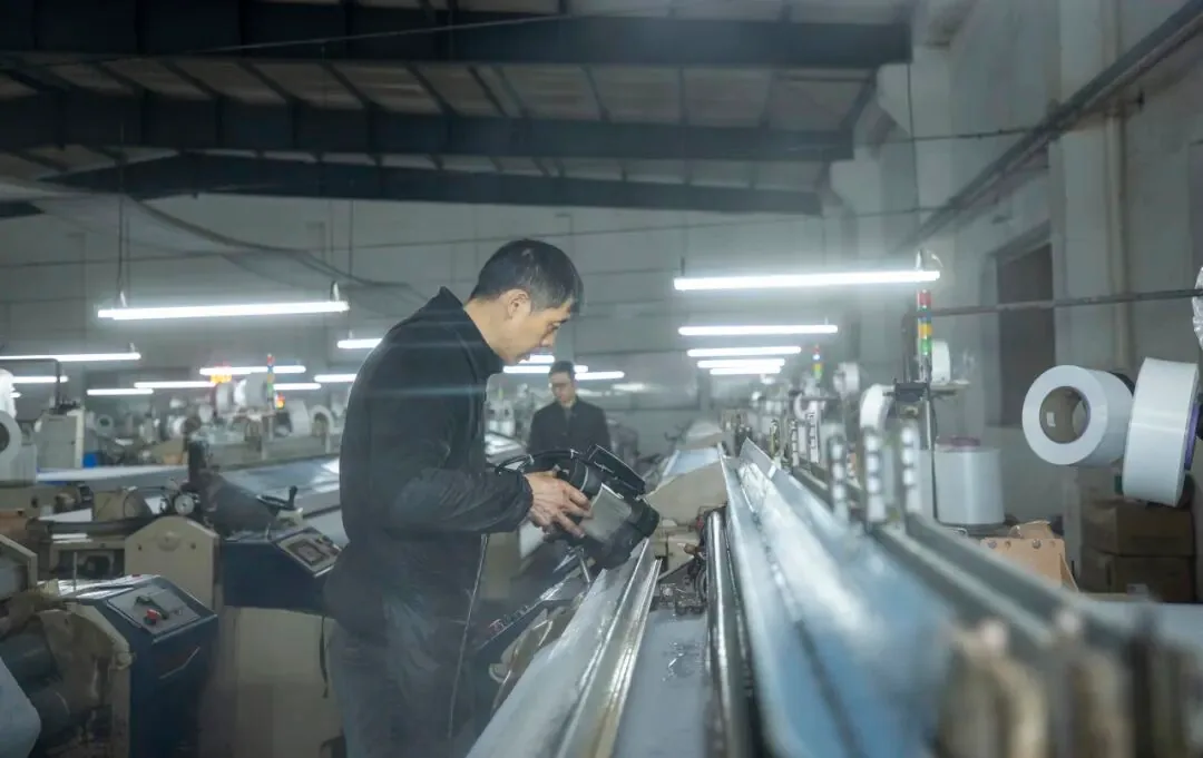An operator working alongside a loom at Gongli Weaving