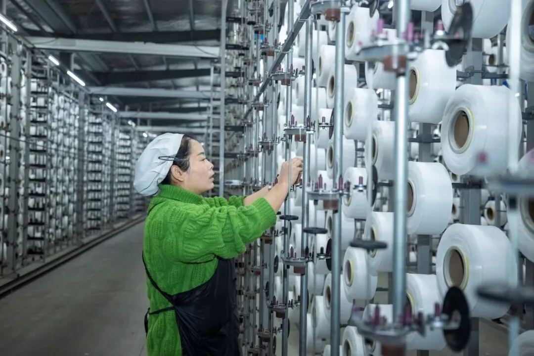 Gongli Weaving operator attending yarn packages on the workshop creel